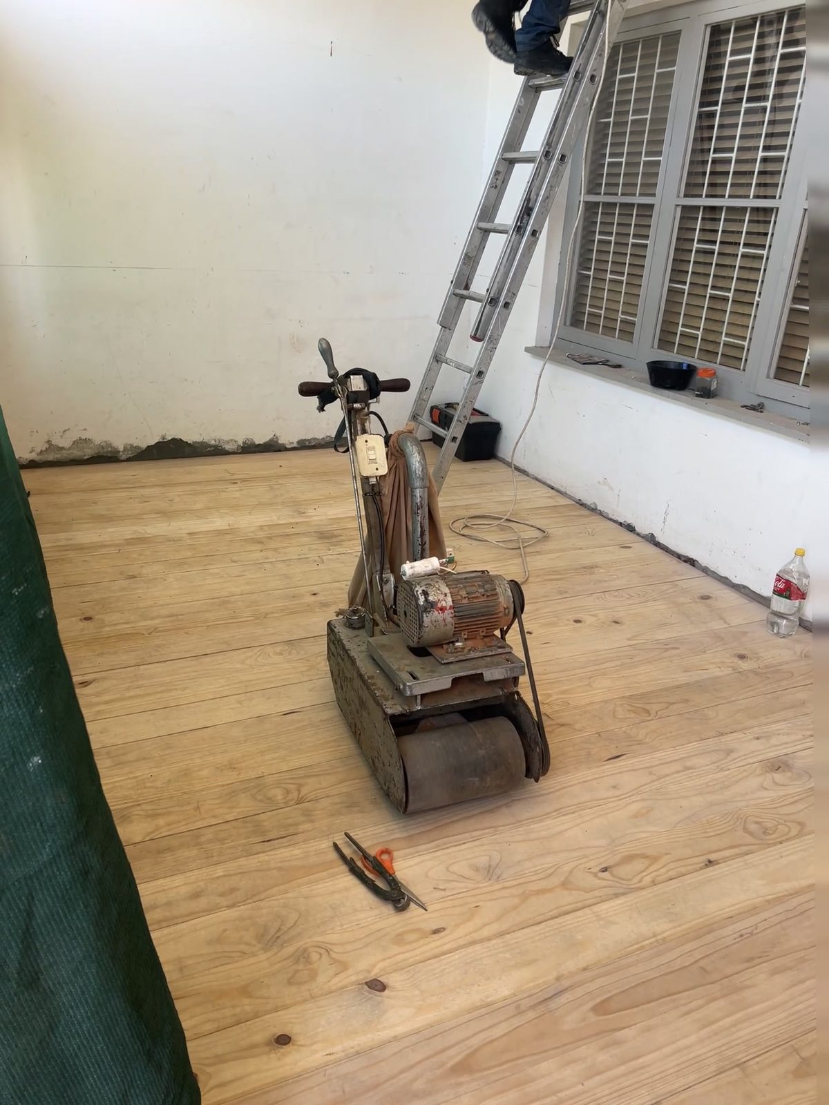 Machine-sanding the new pine floor with a drum sander