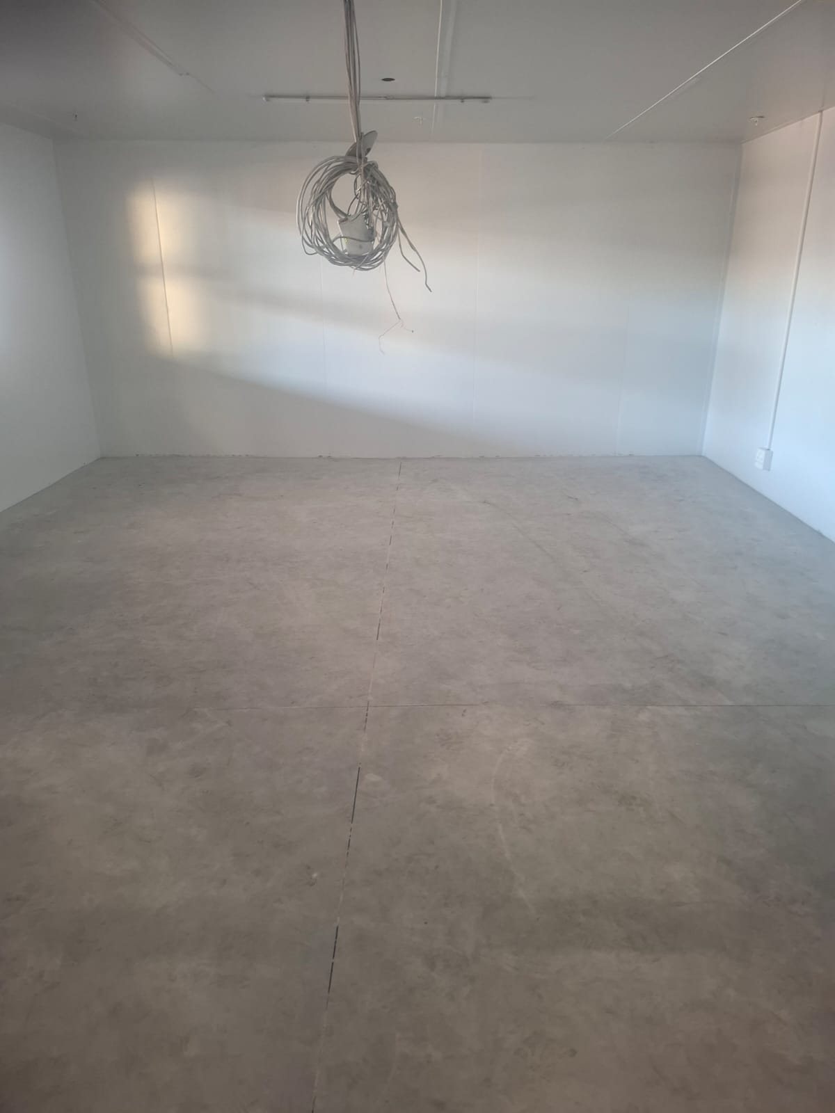Empty holding room with a raw concrete floor ready for a moisture barrier