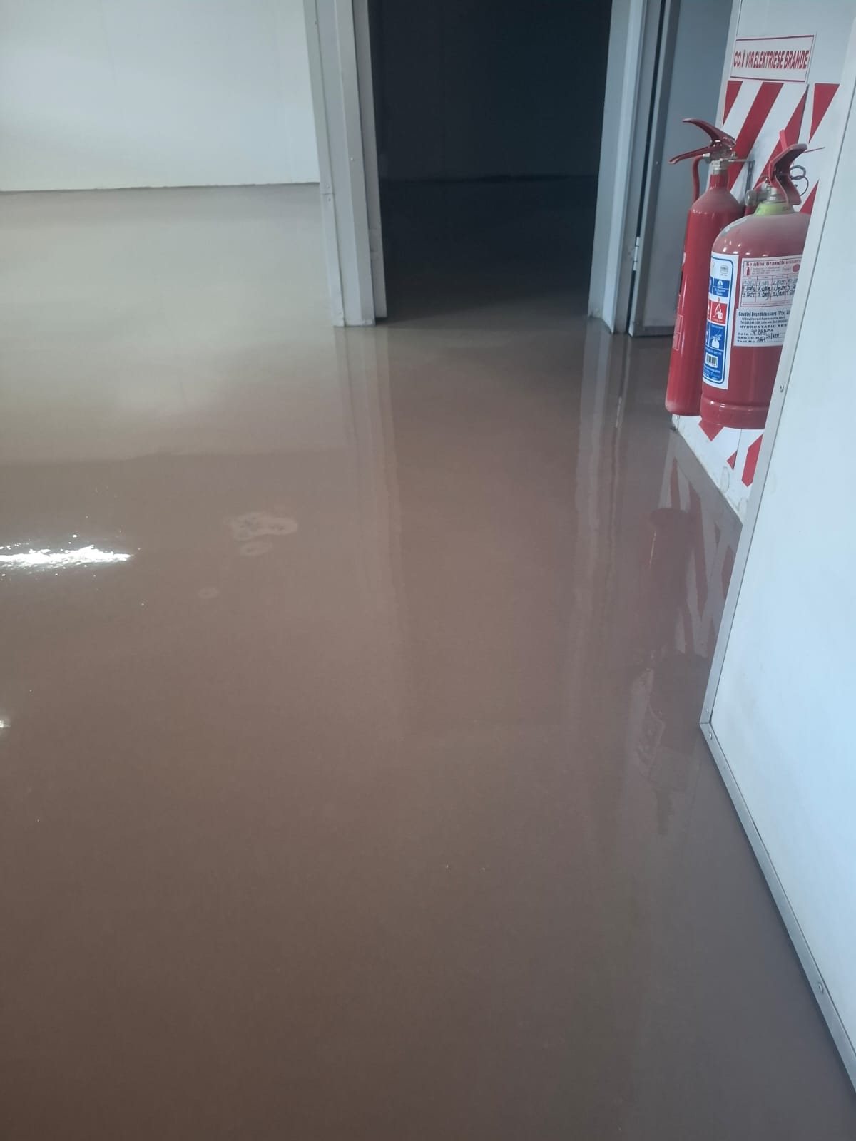 Brown Vaporstop epoxy moisture barrier applied over the slab with sand aggregate broadcast in