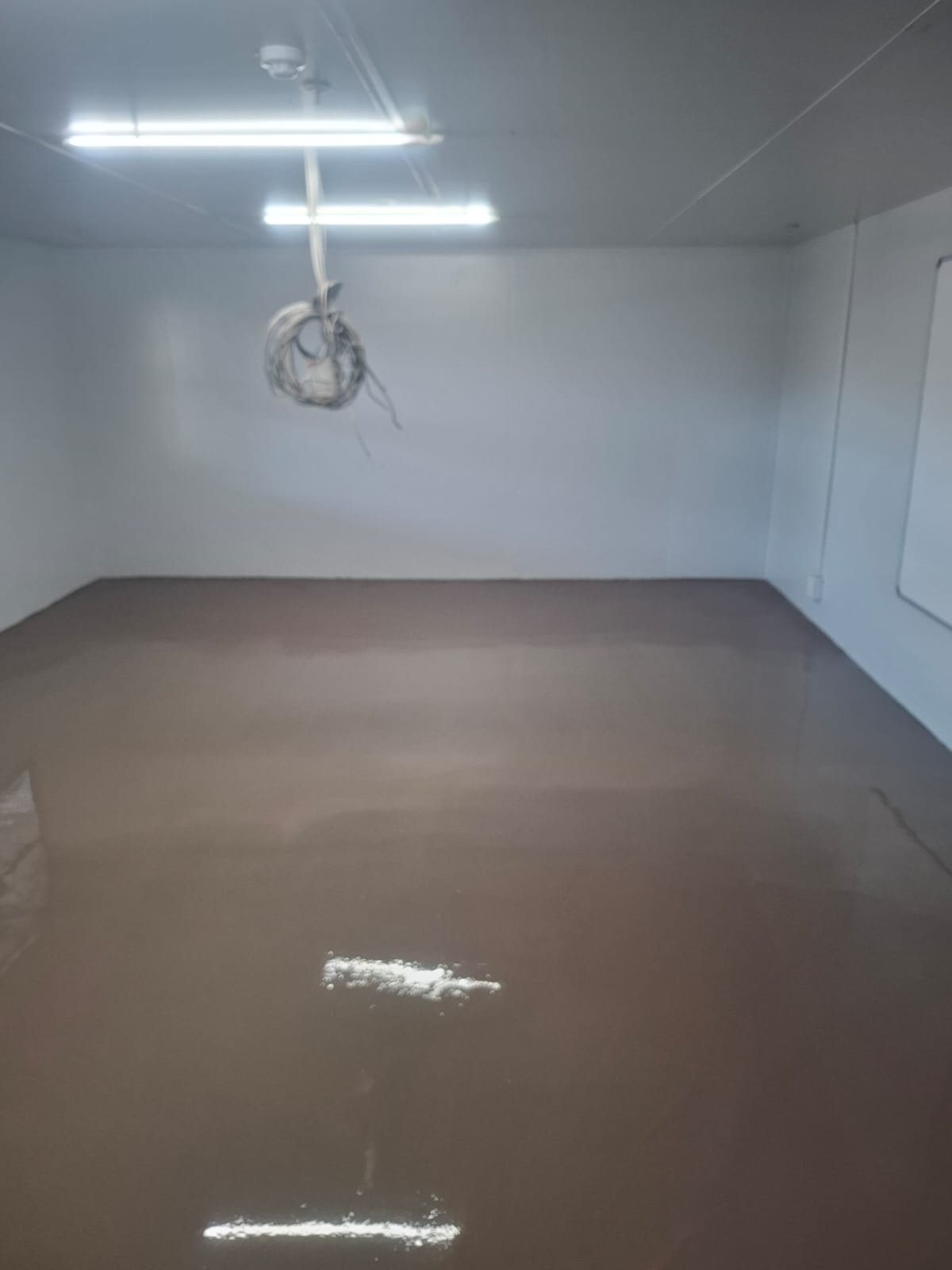 Sealed epoxy barrier curing across the packing room before self-levelling